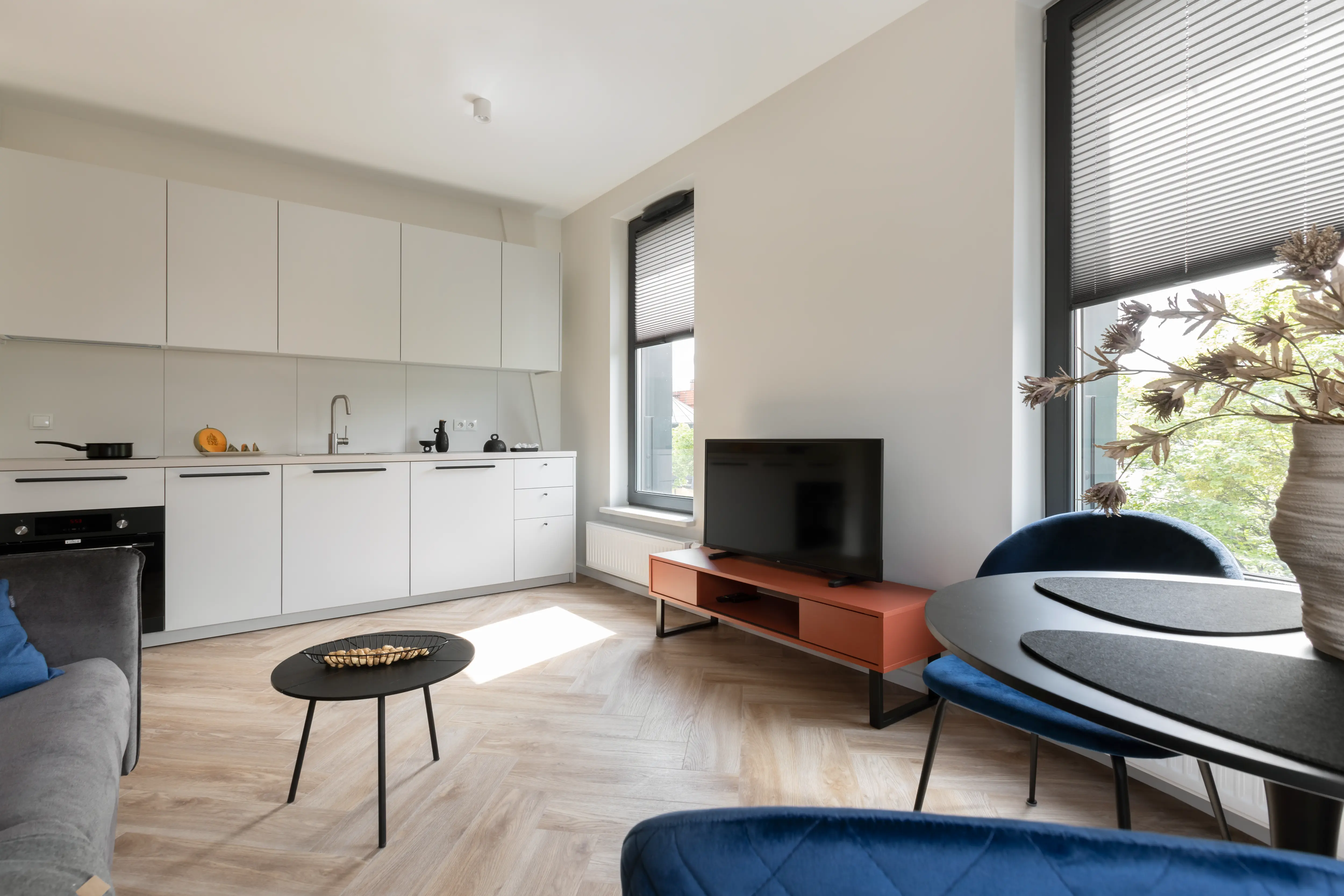 Ein Wohnzimmer mit Parkettboden, weißen Wänden und Möbeln