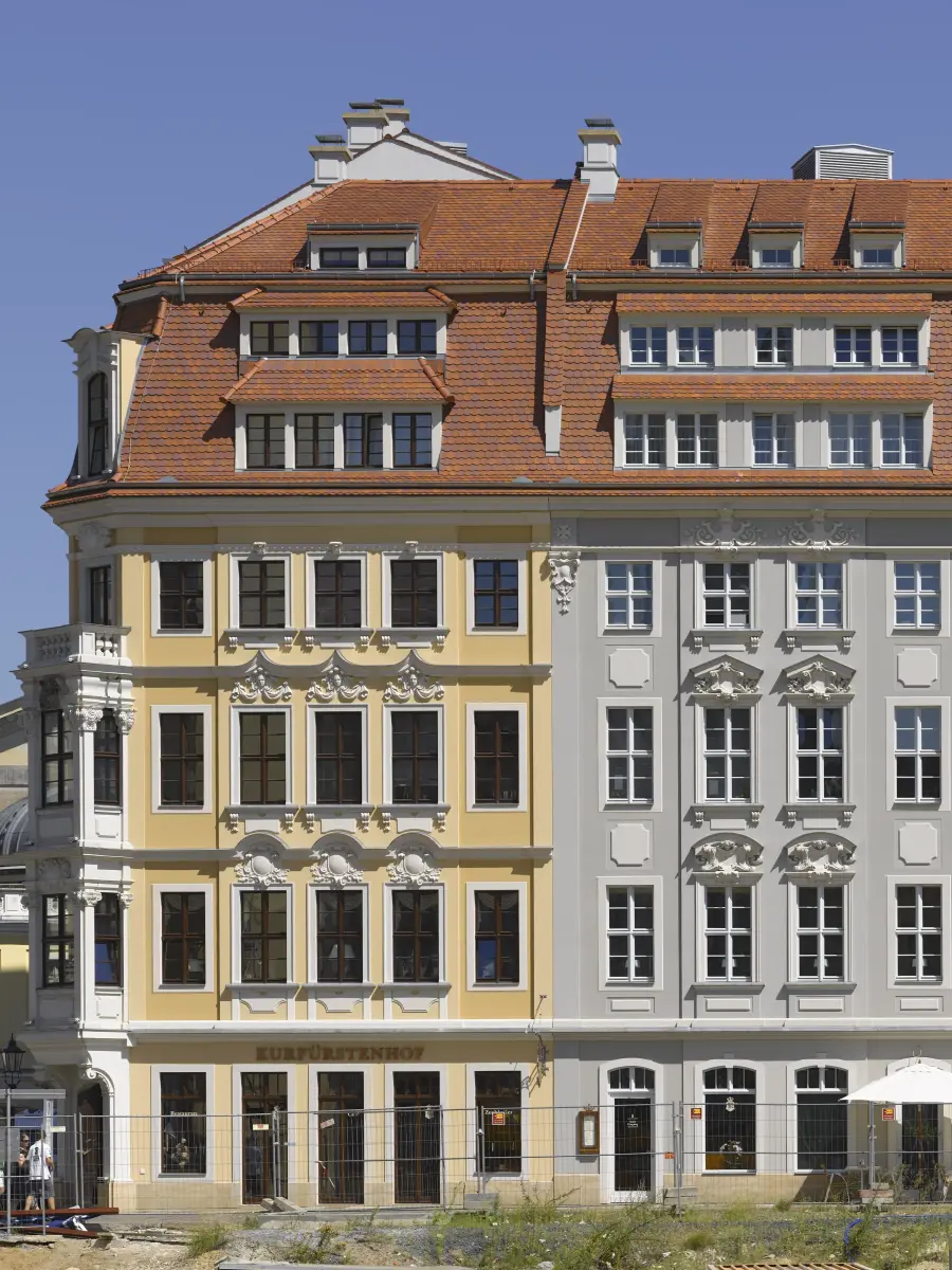 Blick auf gelbe und graue Stilfassade mit Gastronomie im EG