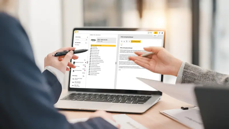 zwei Männer gucken auf einen Screen der Brillux Website
