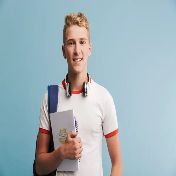 Schüler posiert mit Schulsachen vor blauer Wand.
