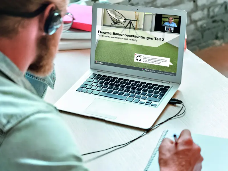 Mann sitzt vor einem Laptop mit einer Live Veranstaltung und notiert sich etwas auf einem Block