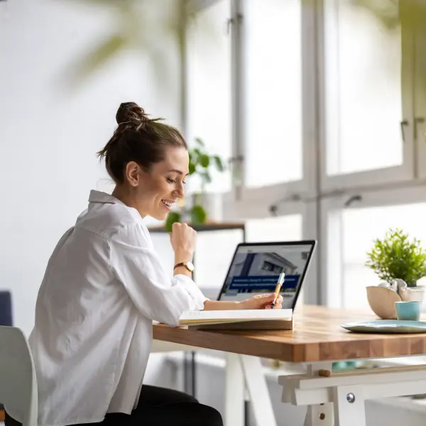 Eine junge Frau sitzt an einem Schreibtisch mit Laptop