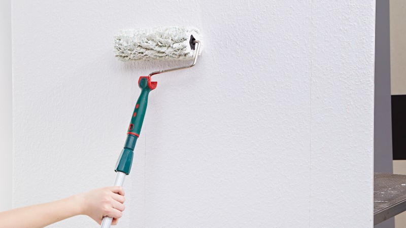 Eine weiße Raufaserwand mit rotem Schrank und Deko