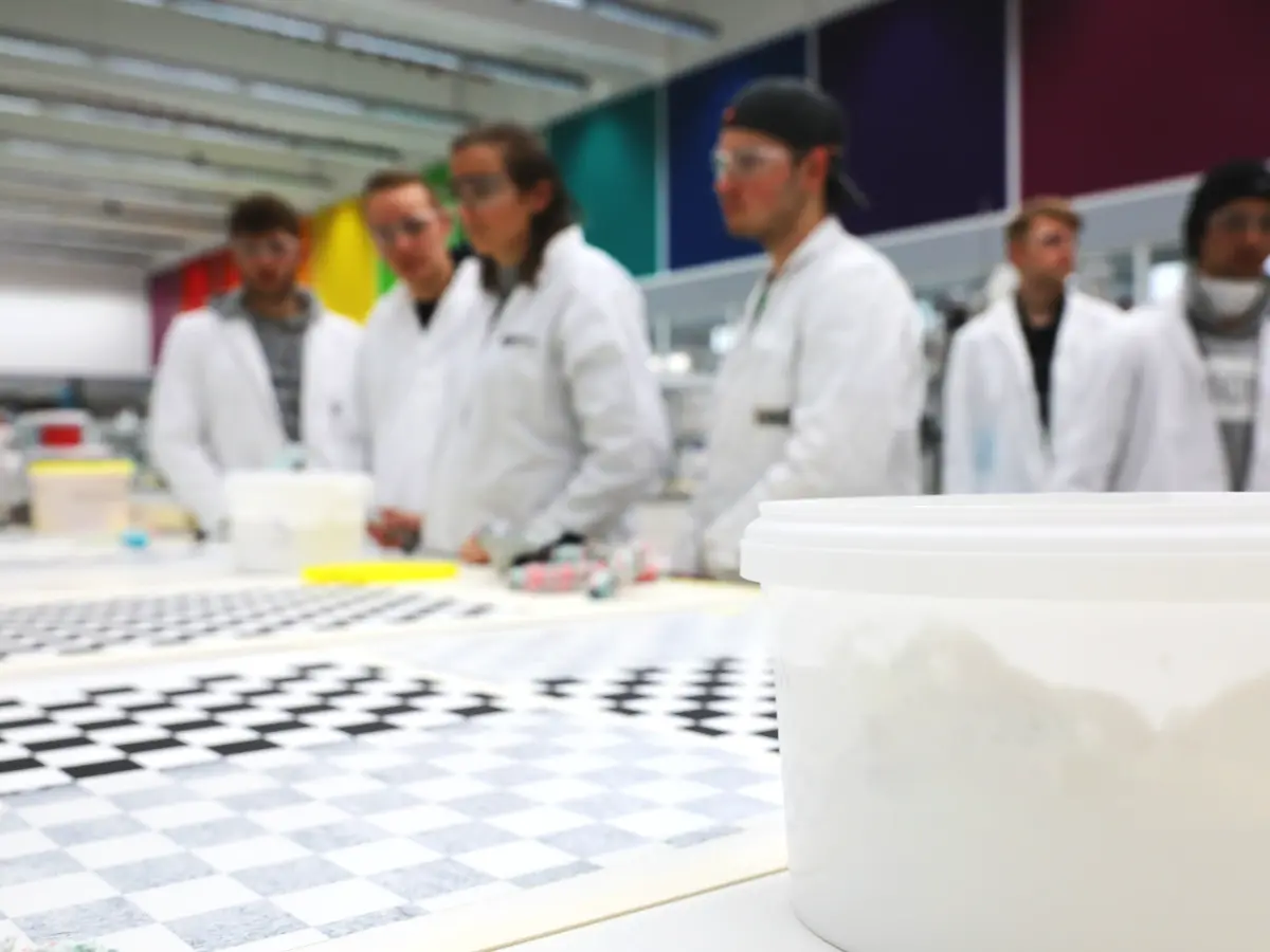 Personen stehen an einem Tisch mit Kacheloptik