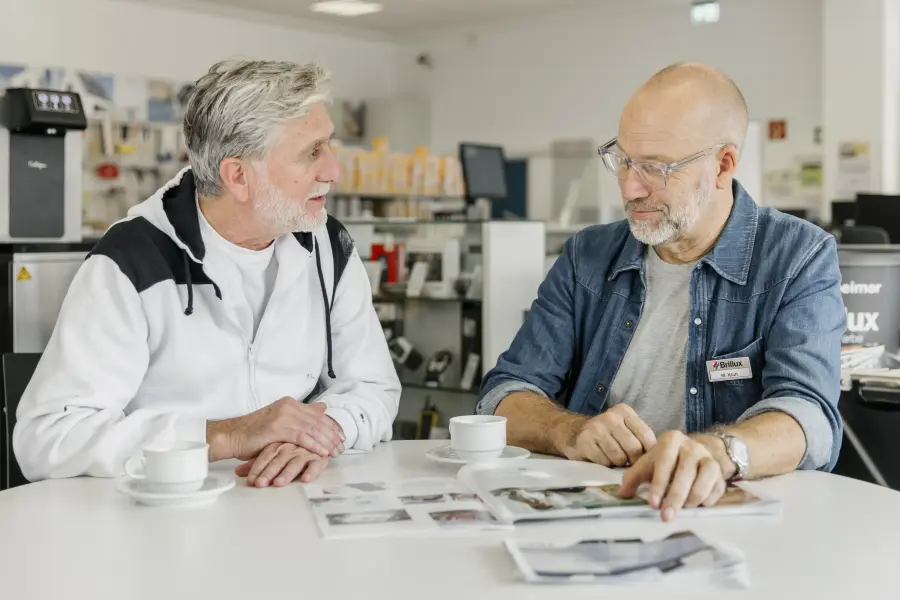 zwei Männer sitzen an einem Tisch und beraten sich über Zeitschriften