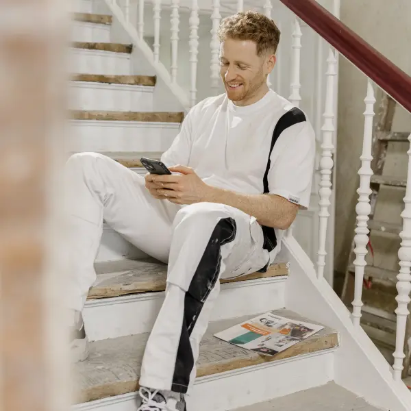 Maler sitzt auf einer Treppe mit Handy in der Hand