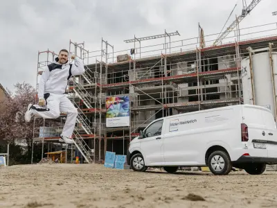 Maler springt vor dem Firmenauto in die Höhe