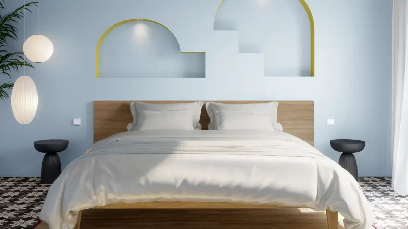 Großes Bett in Beigetönen vor einer hellblauen Wand