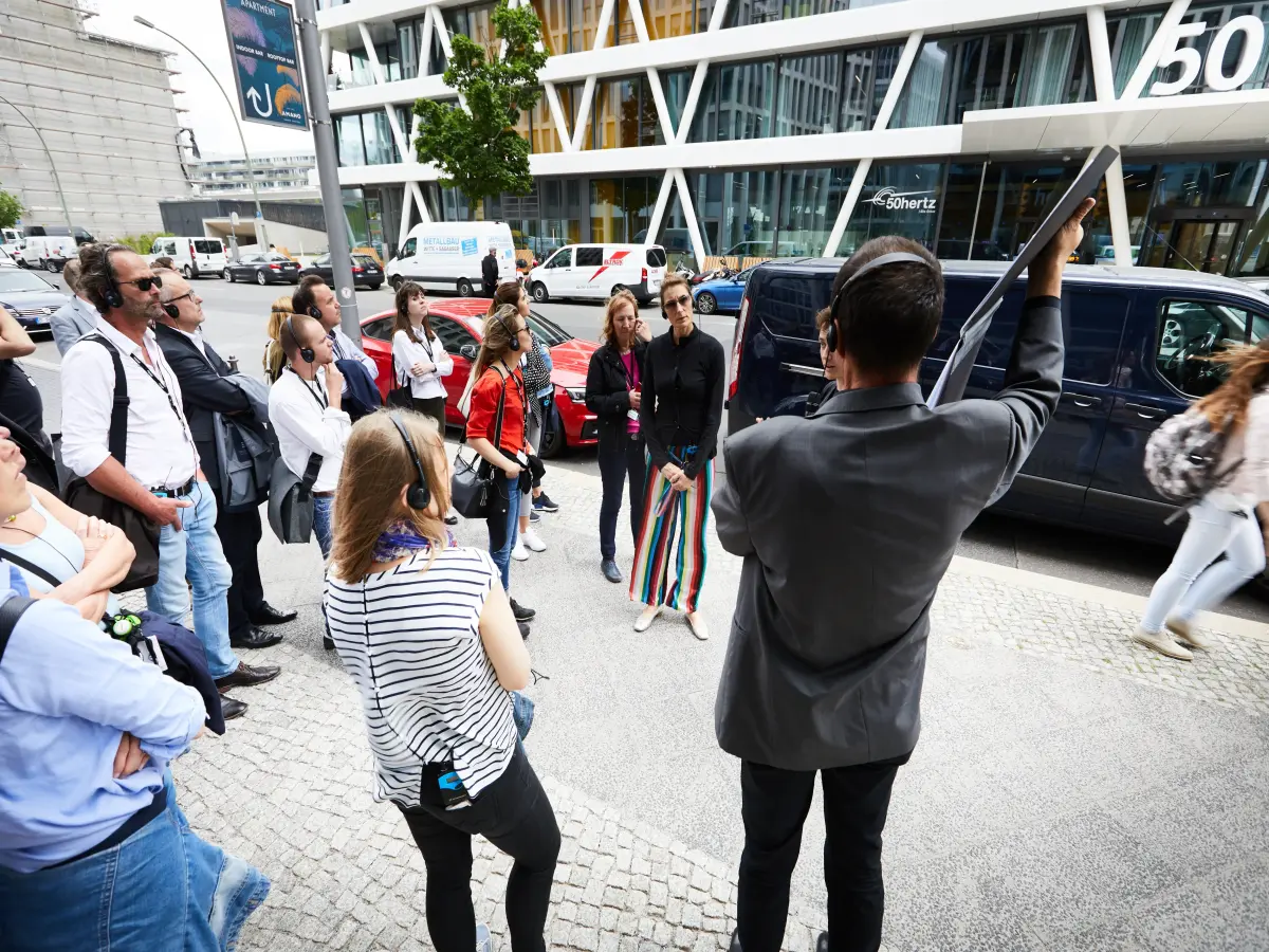 Berlin: Es sein einige Personen zu sehen, die draußen stehen und Kopfhörer tragen.