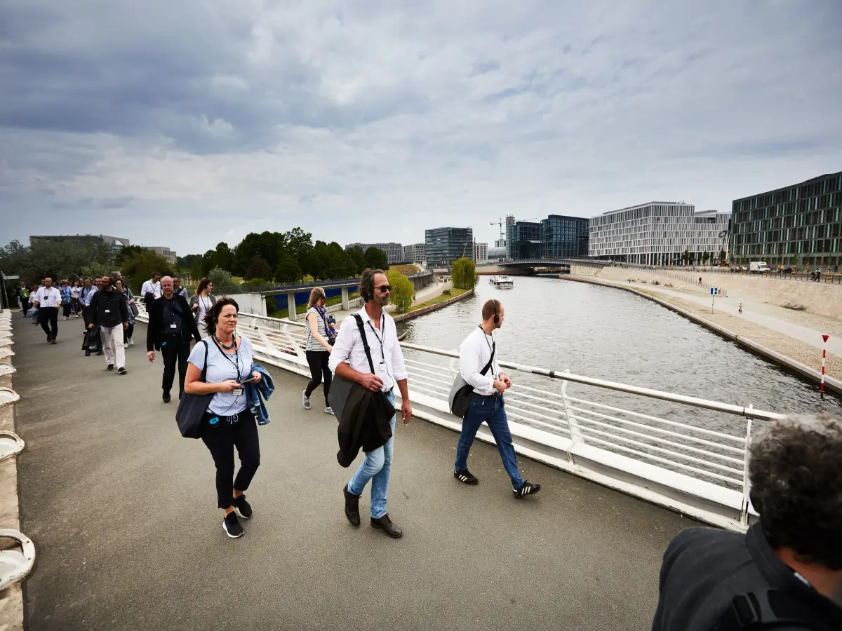 Berlin: Menschen auf einer brücke sind zu sehen. Im Hintergrund ist ein Fluss.