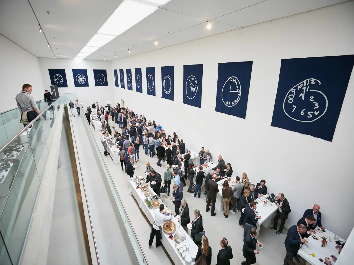Düsseldorf: Es sind viele Menschen ein einer Ausstellung zu sehen, die sich am Buffet bedienen.