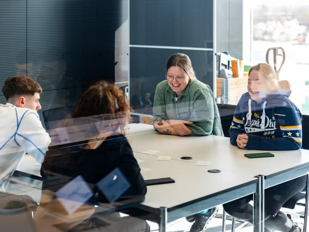 Vier Personen sitzen an einem Tisch und lachen