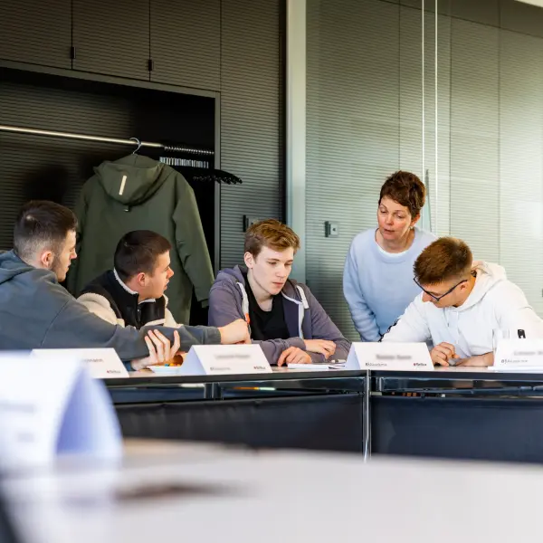 Gruppe von jungen Leuten mit Namensschildern am Tisch 