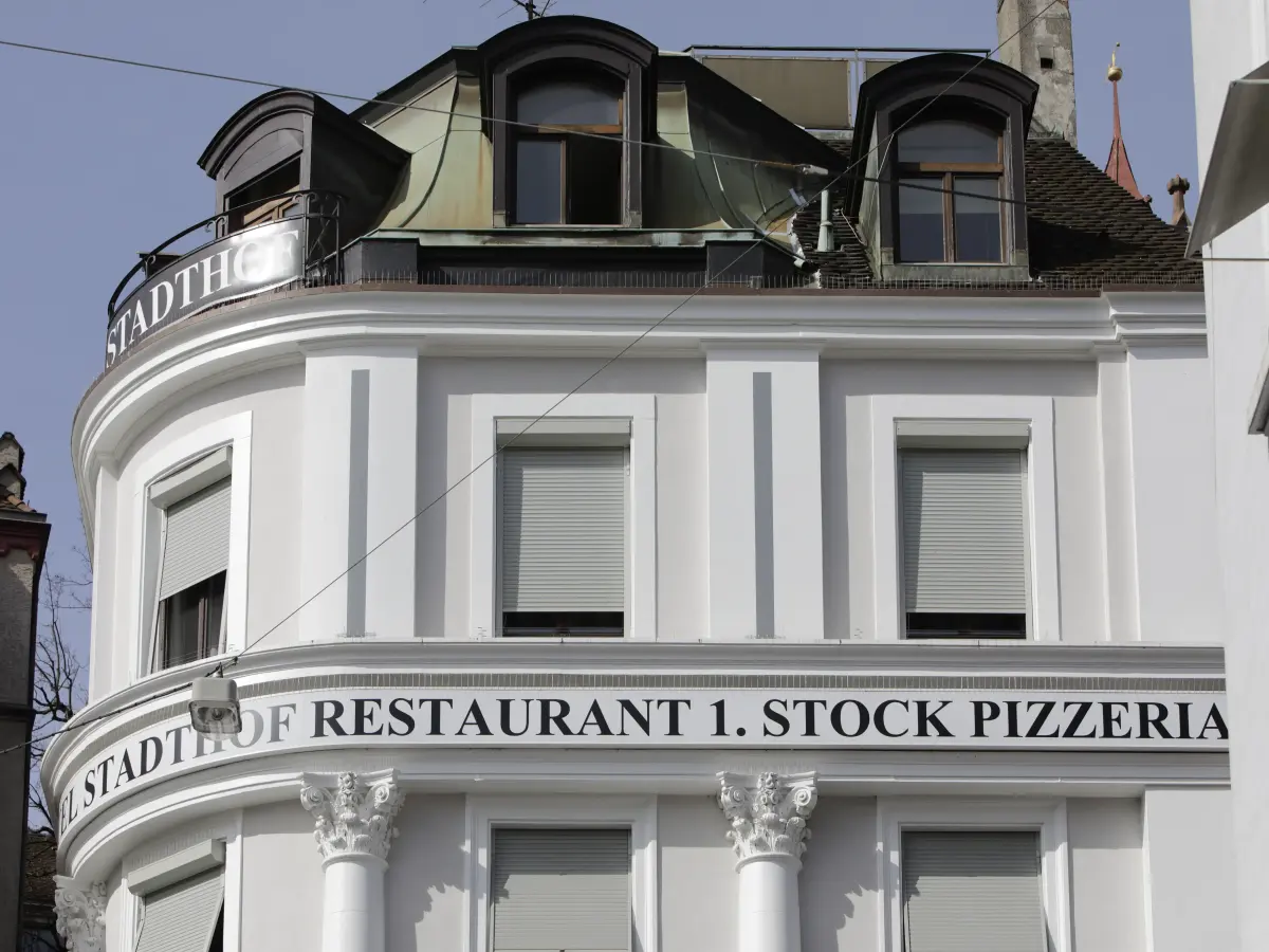 Oberer Teil eines weißen Gebäudes mit Dachgauben und Schriftzug.