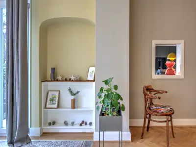 Ein heller Raum mit dekorativem Wandregal, Pflanze, Holzstuhl und ruhigen Farbtönen.