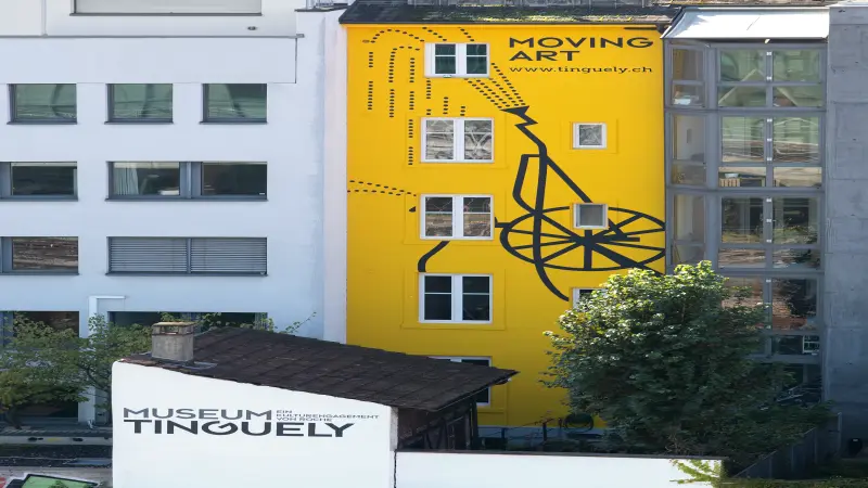 Gelbes Gebäude mit schwarzem Kunstwerk, Schriftzug "MOVING ART"