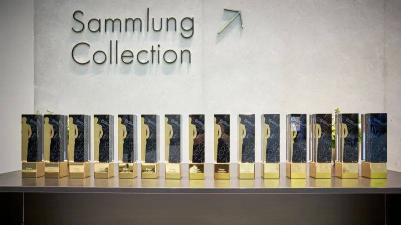 Viele Brillux Design Awards vor einen Betonwand nebeneinandergestellt