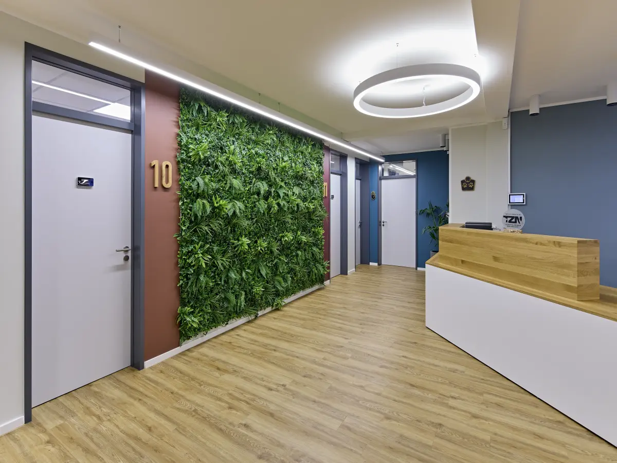 Heller Flur einer Tierarztpraxis mit grüner Pflanzenwand und modernem Empfang.