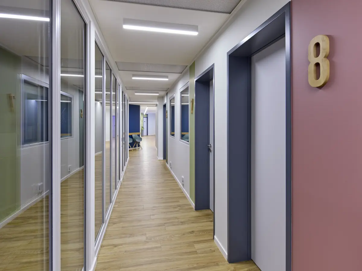 Heller Praxisflur mit Türen, Glasfront und Holzfußboden.