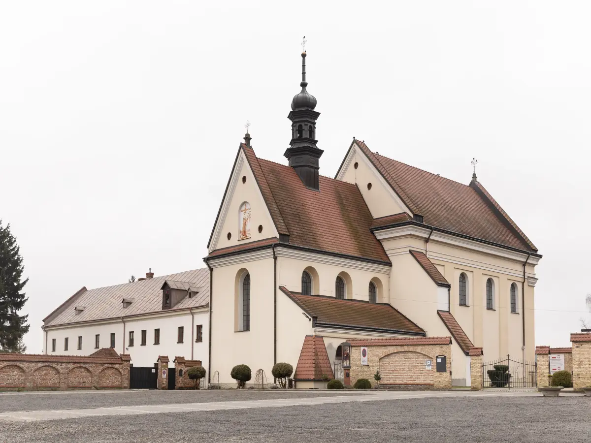 Klosterkirche in Polen, mit hellen Mauern, rotem Ziegeldach und einem hohen Glockenturm.