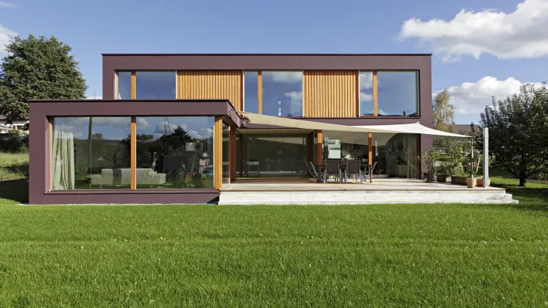 Ein bordeaux farbendes Haus mit grünem Rasen