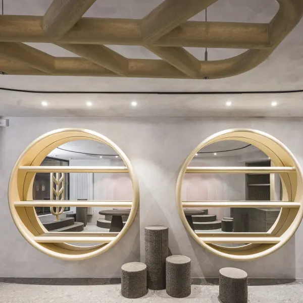  Zwei große, runde, holzgerahmte Schaufenster in einer modern gestalteten Boutique mit heller, grauen Wand.