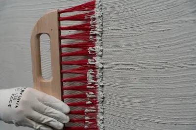 Ein Besen wird über eine Fassade gezogen
