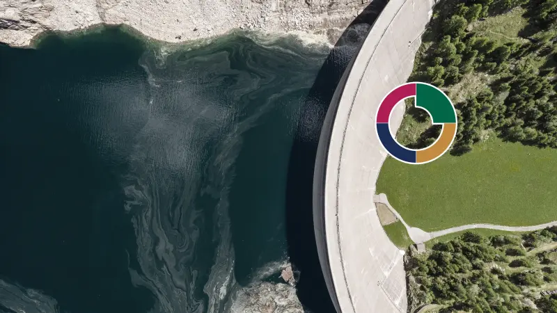 Ein Staudamm trennt Wasser und eine grüne Landfläche voneinander.