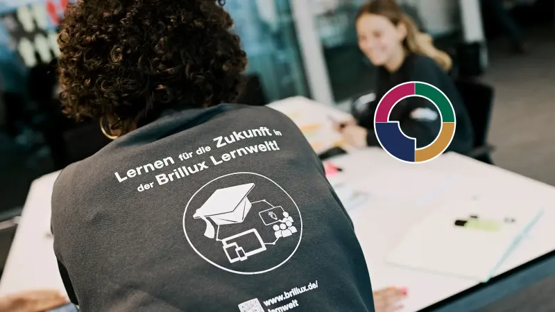 Zwei junge Personen sitzen an einem Bürotisch über Projektarbeit
