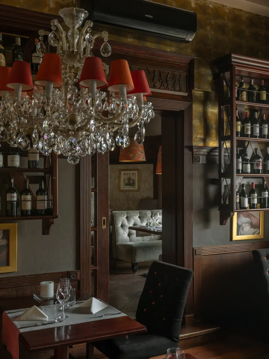 Eleganckie wnętrze restauracji z kryształowym żyrandolem i regałami na wino.