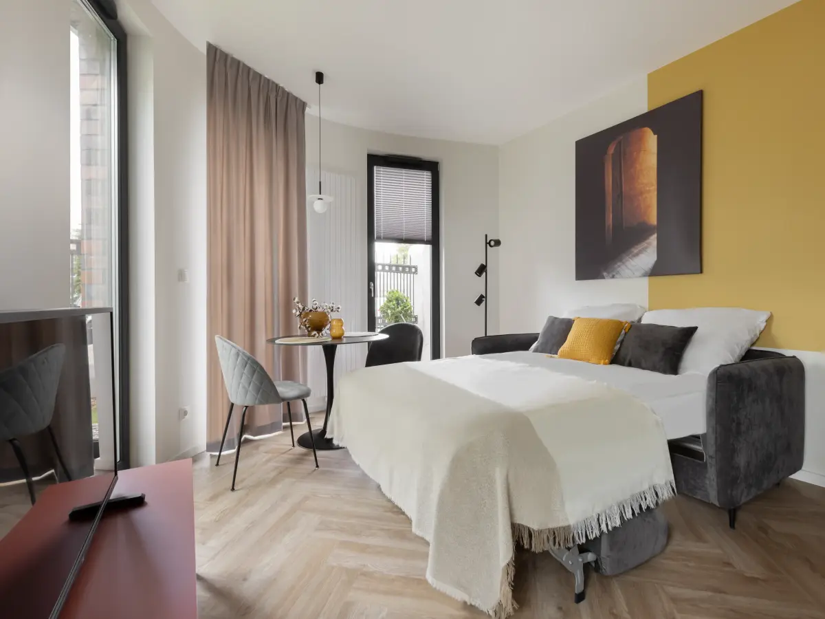 Schlafzimmer mit großem weißen Bett und gelber Wand