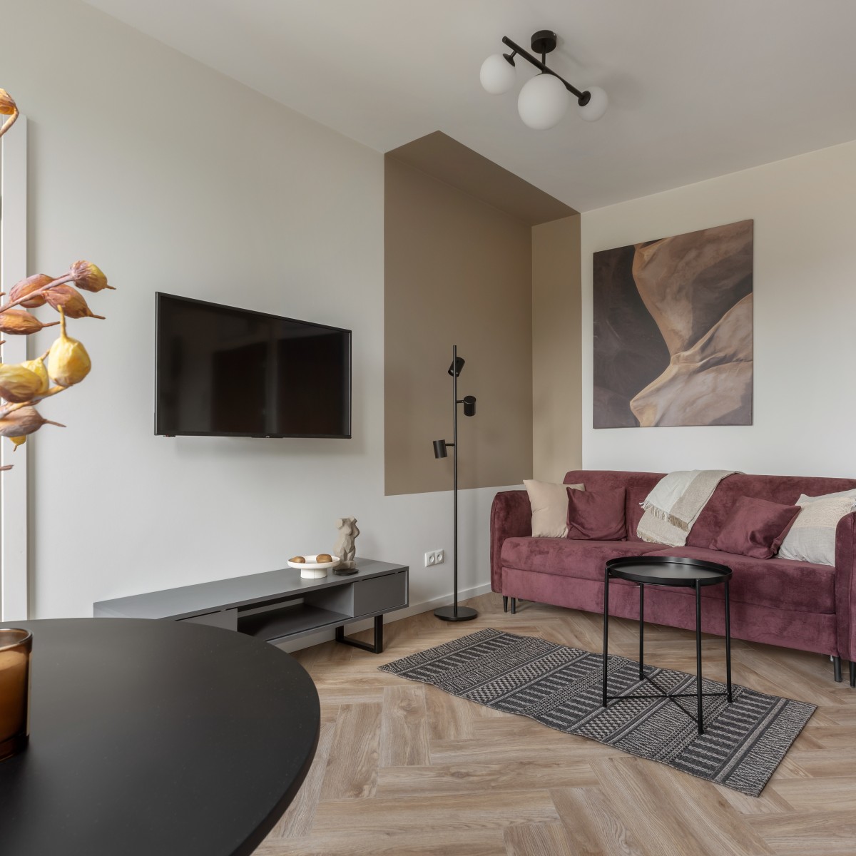 Weinrotes Sofa vor weiß-grauer Zimmerwand