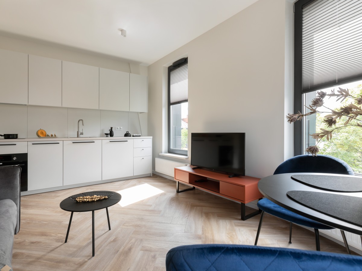 Ein Wohnzimmer mit Parkettboden, weißen Wänden und Möbeln