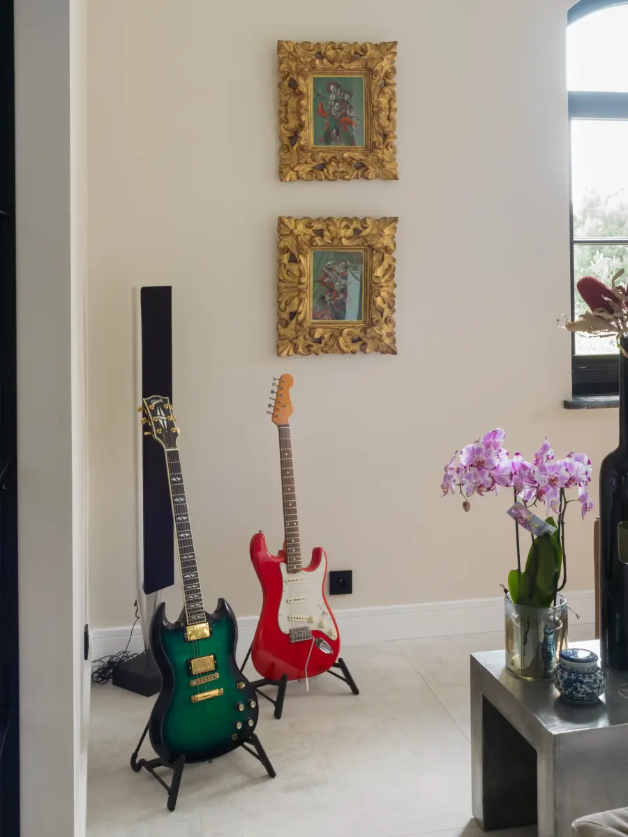 Zwei Gitarren in der Ecke sowie zwei Bilder im goldenen Rahmen an der Wand