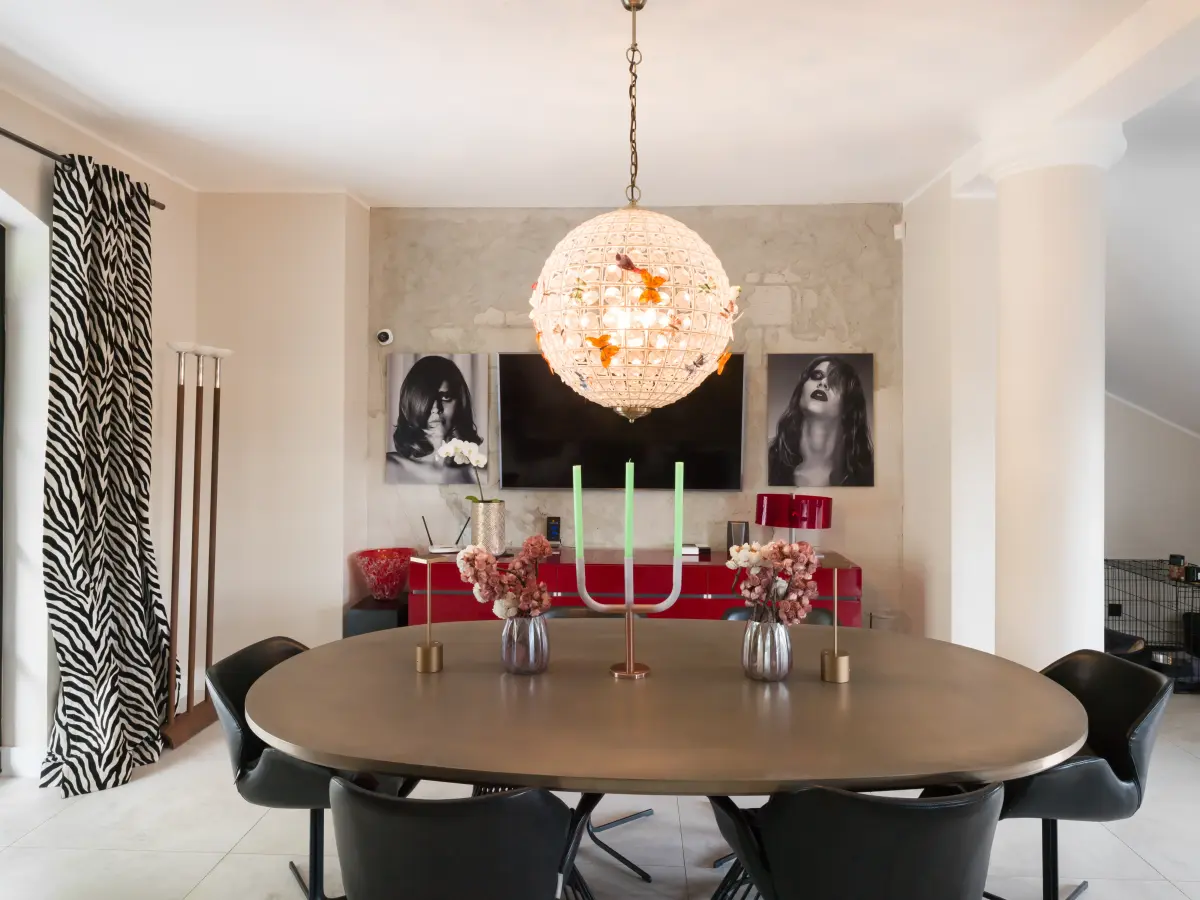 Ovale Holztisch im Esszimmer mit roter Kommode im Hintergrund