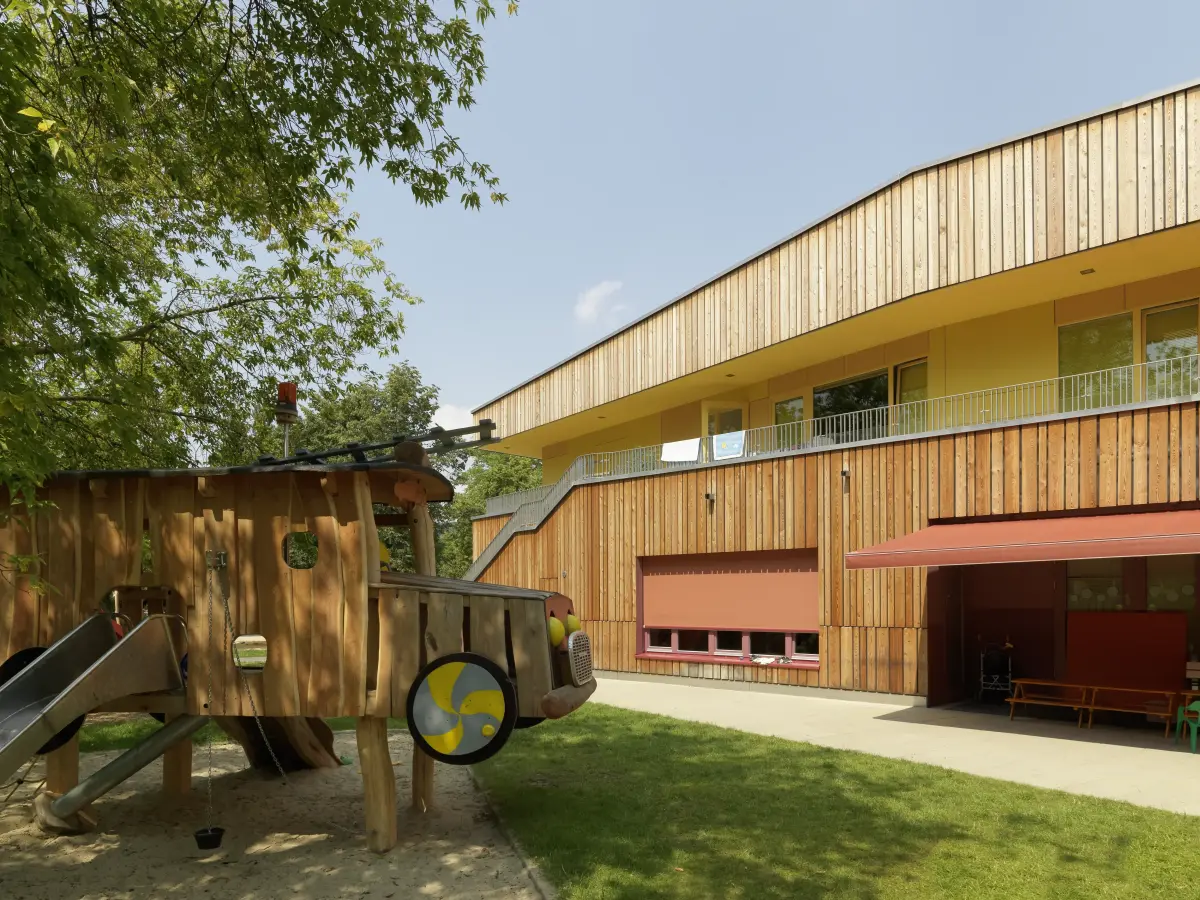 Spielhaus mit Holzfassade im Hintergrund 