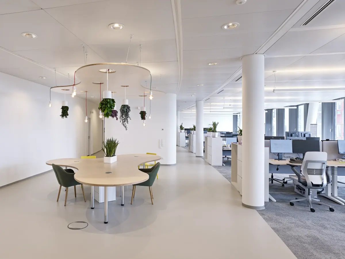 unterschiedliche Arbeitsumgebungen - neben einem verspielten Meetingstisch die Standard Schreibtisch Reihen