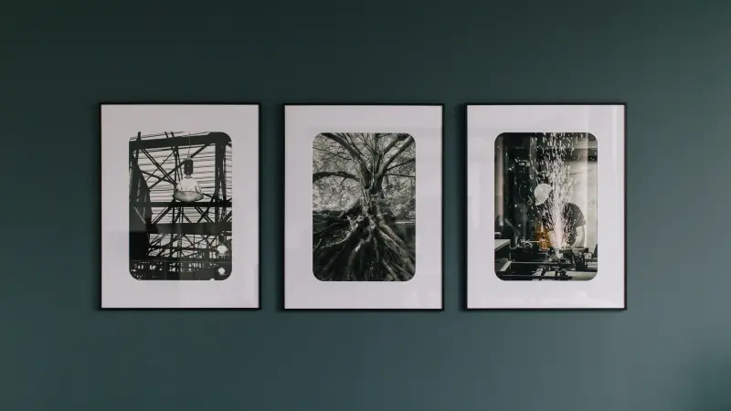 drei gerahmte Bilder an einer dunklen petrolfarbenen Wand