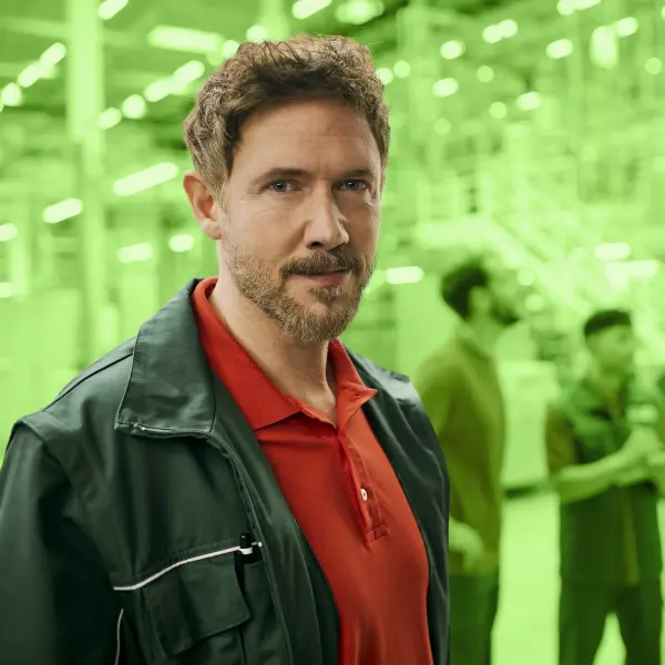 Ein mittelalter Mann in Produktions-Arbeitskleidung schaut in die Kamera