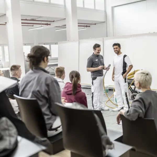 Ein Maler-Ausbilder zeigt mehrere Schülern eine Maler-Technik