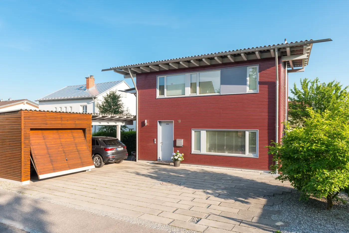 Ein rotes Holzhaus mit Garage und Auto
