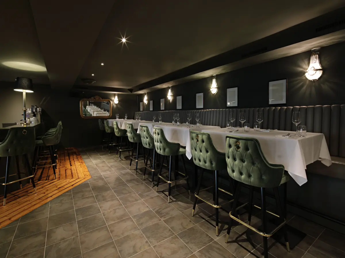 dunkles Interieur einer Bar mit Holzboden und grünen Sitzen