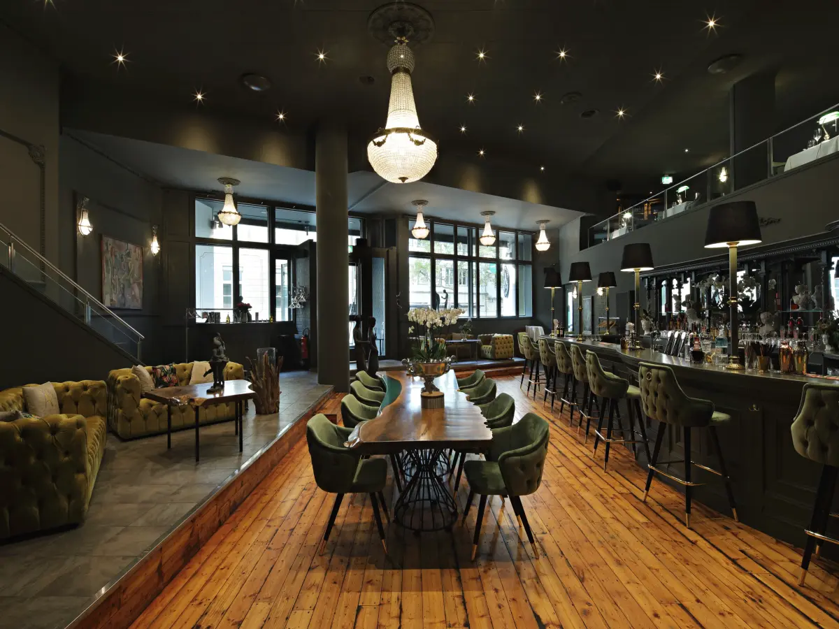 dunkles Interieur einer Bar mit Holzboden und grünen Sitzen