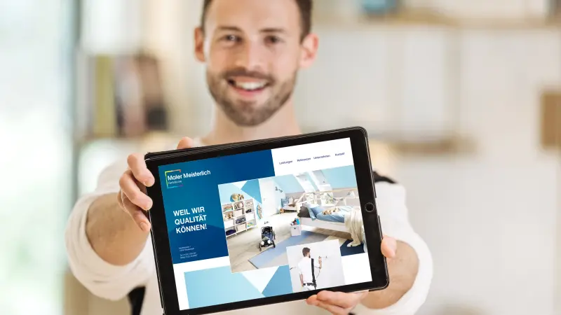 Mann hält stolt ein Tablet mit seiner Website in die Kamera