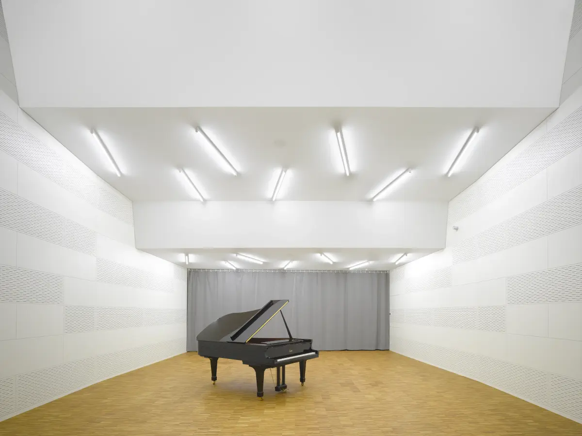 weißer Proberaum mit einer gestuften Decke und einem Flügel in der Mitte