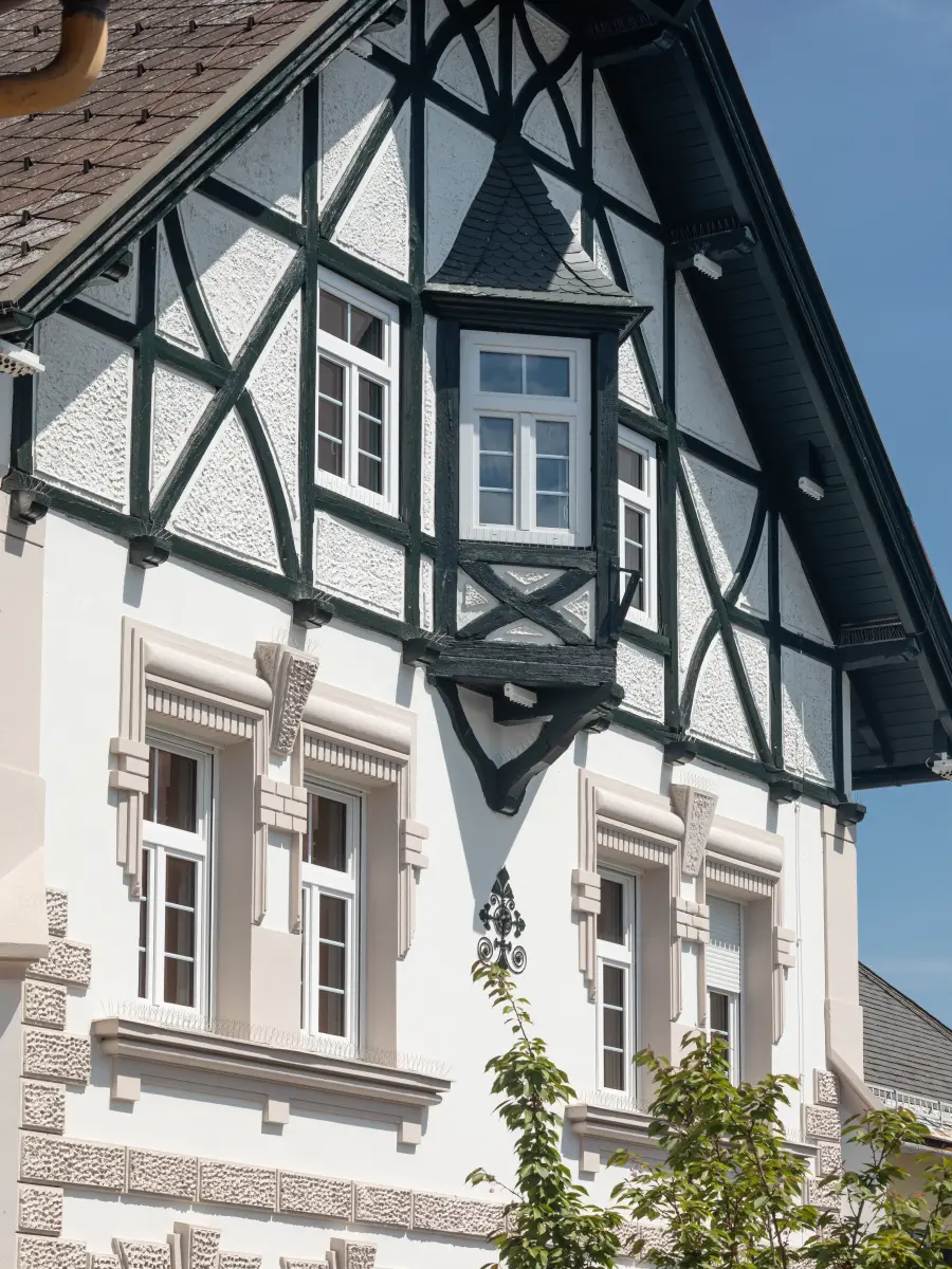 Nahaufnahme des oberen Teils eines Hauses mit dunklem Fachwerk-Giebel und einem kleinen Erkerfenster.