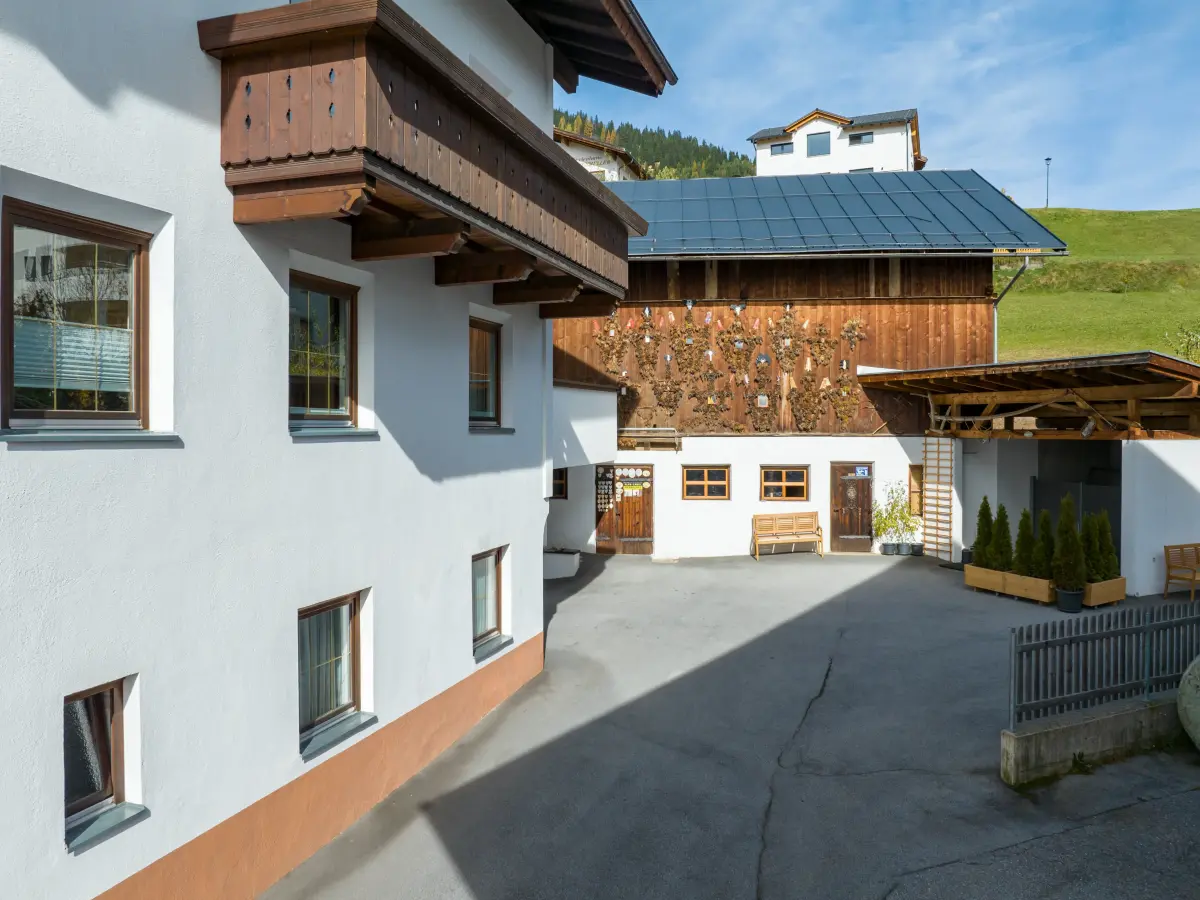 Hofansicht mit modernisiertem Wohnhaus und traditionellem Holzgebäude in Fiss.