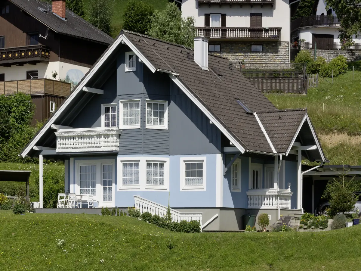 Blaues Landhaus in der Natur, frontal und auf Augenhöhe aufgenommen.