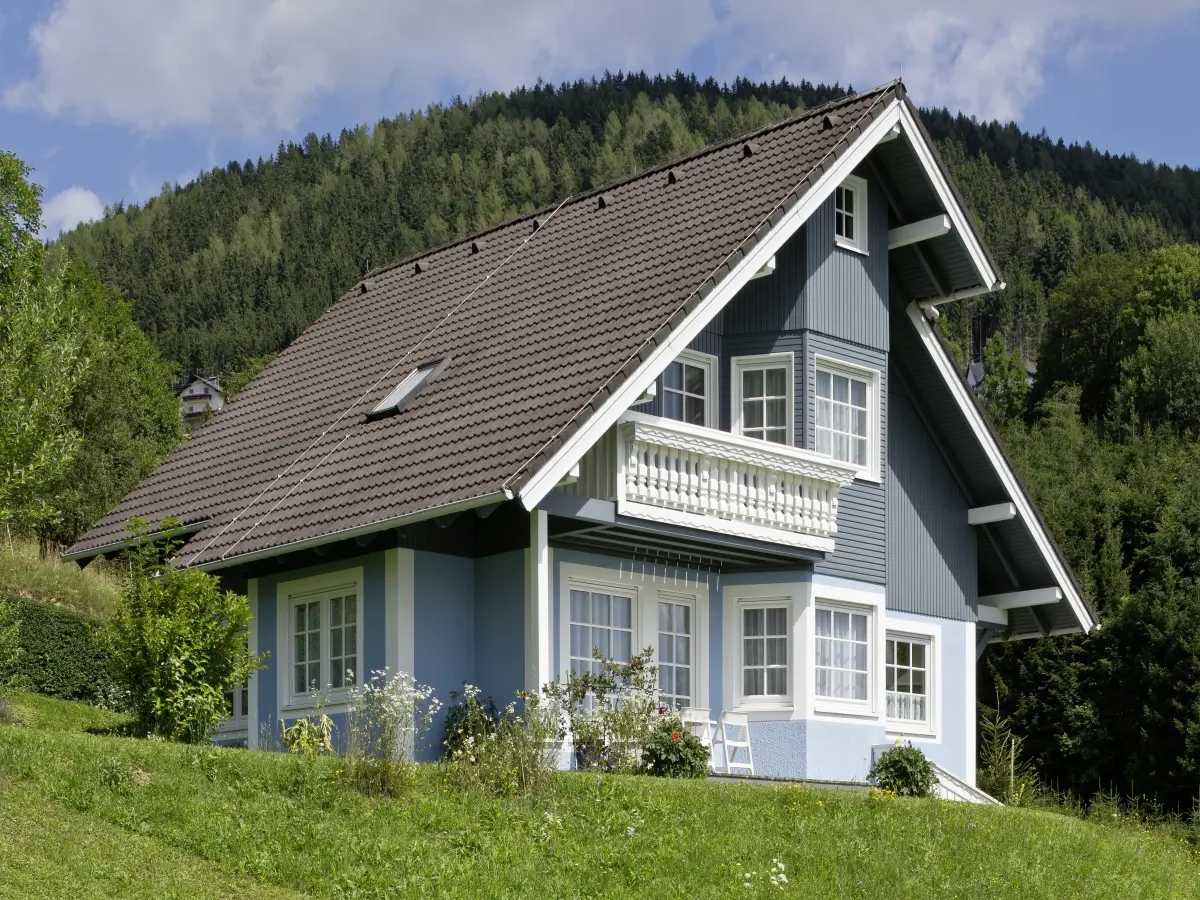 Blaues Landhaus inmitten der Natur, aus einer Untersicht aufgenommen.
