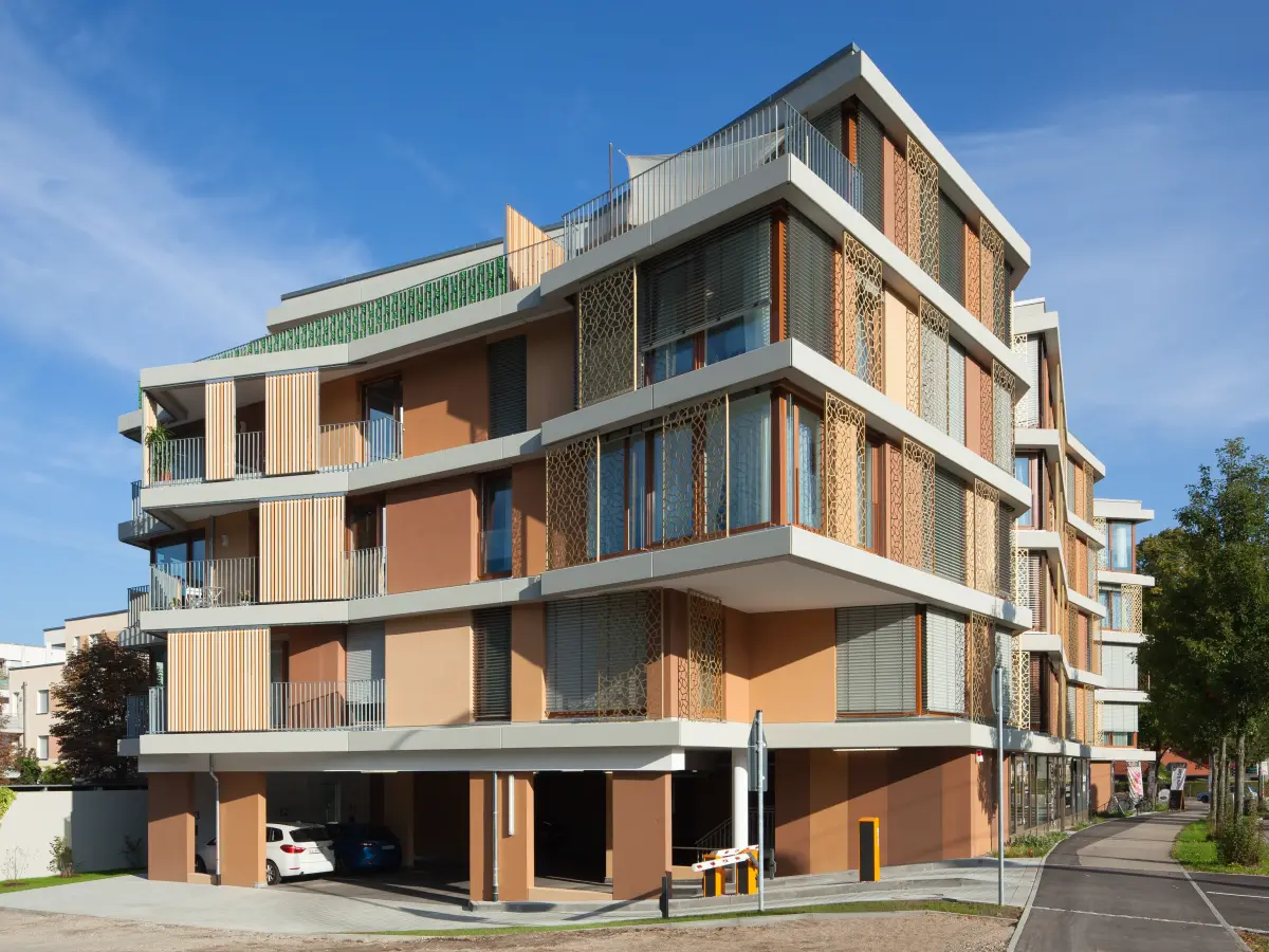 Edificio residenziale moderno a più piani con fasce marcapiano orizzontali bianche, calde tonalità della terra ed elementi decorativi di facciata.